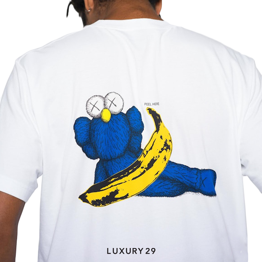 White t-shirt with a blue creature holding a yellow banana graphic on the back, brand 'LUXURY 29' visible.