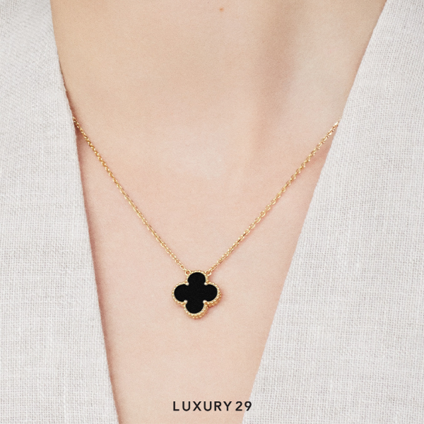 Gold necklace with a clover pendant on a person's neck against a white background, labeled 'Luxury 29'.